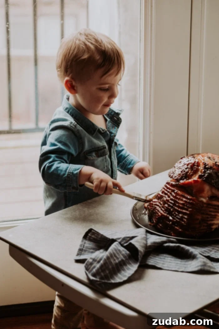 Garlic Honey Mustard Glazed Ham 3 A toddler helping to brush the garlic honey mustard glaze onto a spiral ham, making it a fun family activity.