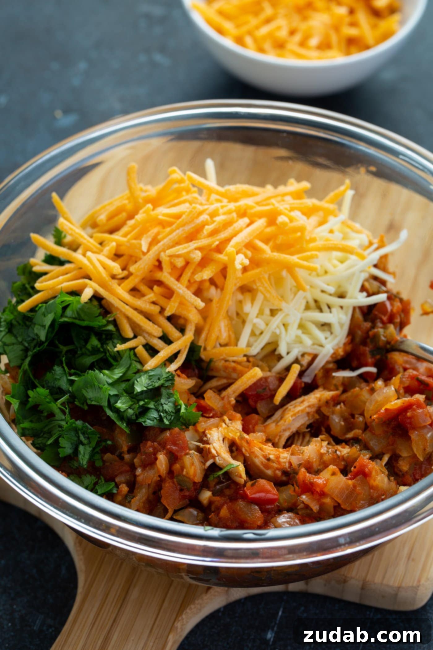 Red Enchilada Sauce A glass bowl with chicken enchilada filling, cilantro, grated cheese, and tortillas.