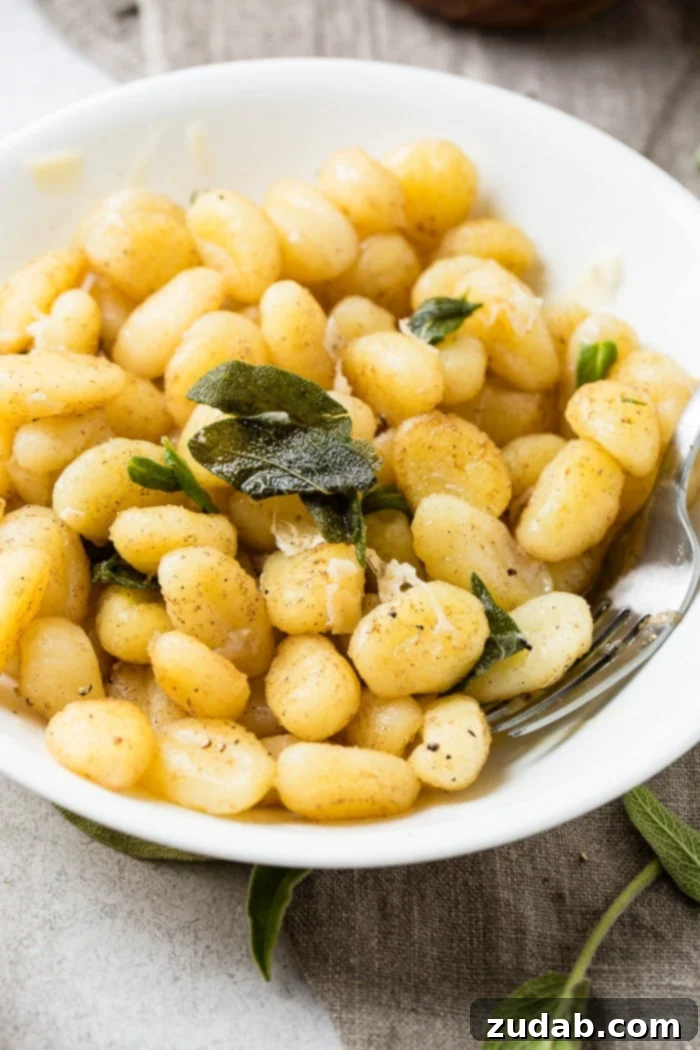 Easy 10-Minute Brown Butter Sage Gnocchi 5 A white bowl with a pile of 10 minute brown butter sage gnocchi on a natural linen naplkin with a fork in the pasta