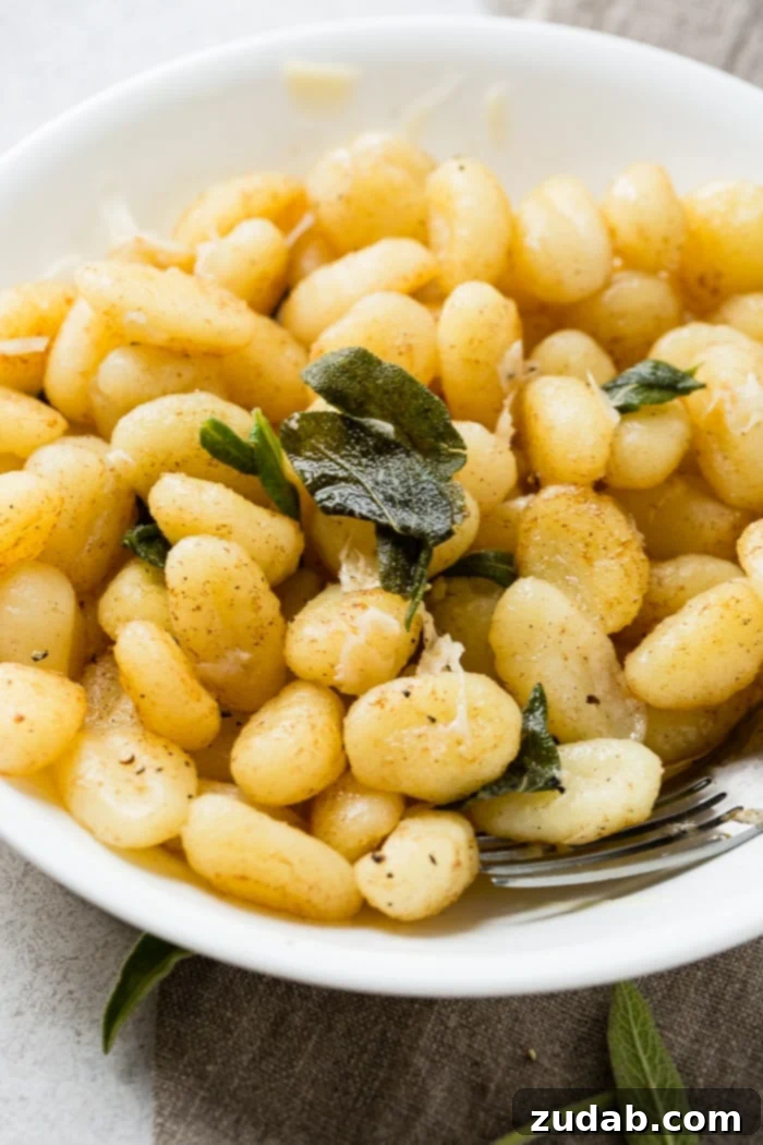 Easy 10-Minute Brown Butter Sage Gnocchi 6 A white bowl with a pile of 10 minute brown butter sage gnocchi on a natural linen naplkin with a fork in the pasta