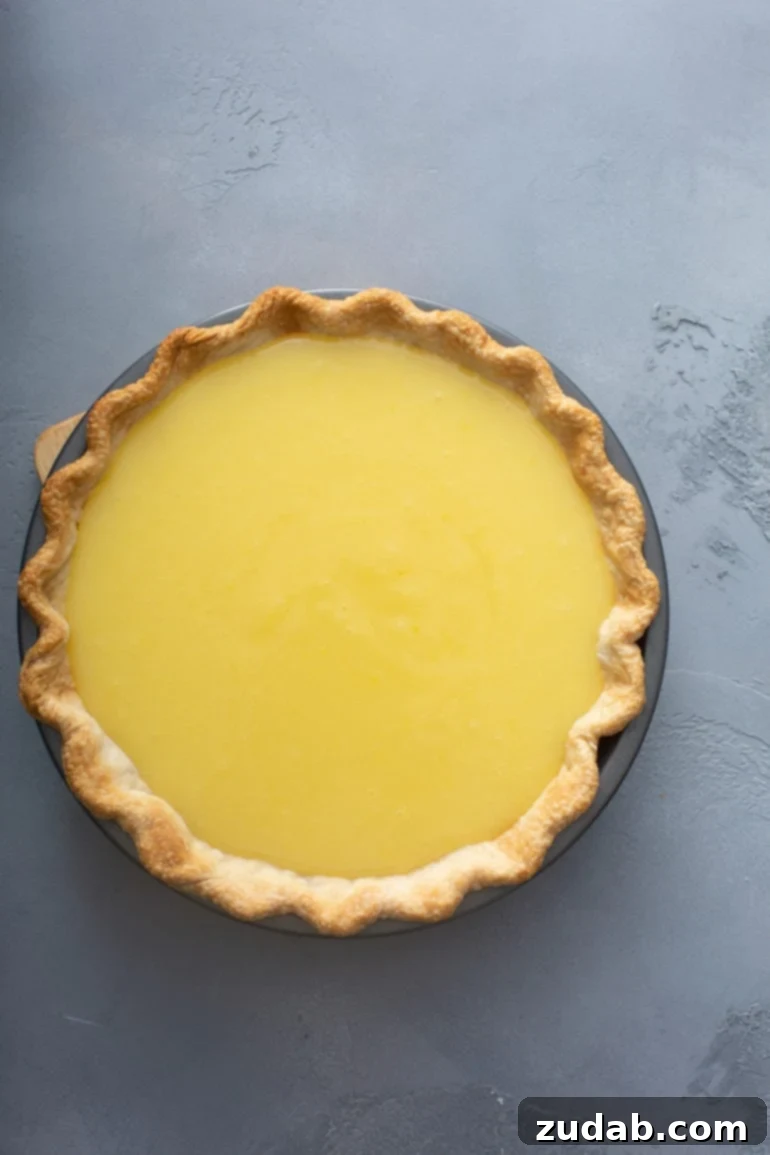 Mom's Secret Lemon Meringue Pie 8 A close-up shot of a freshly assembled lemon pie, with its bright yellow filling and a lightly golden-brown, perfectly baked crust visible before the meringue topping is added.