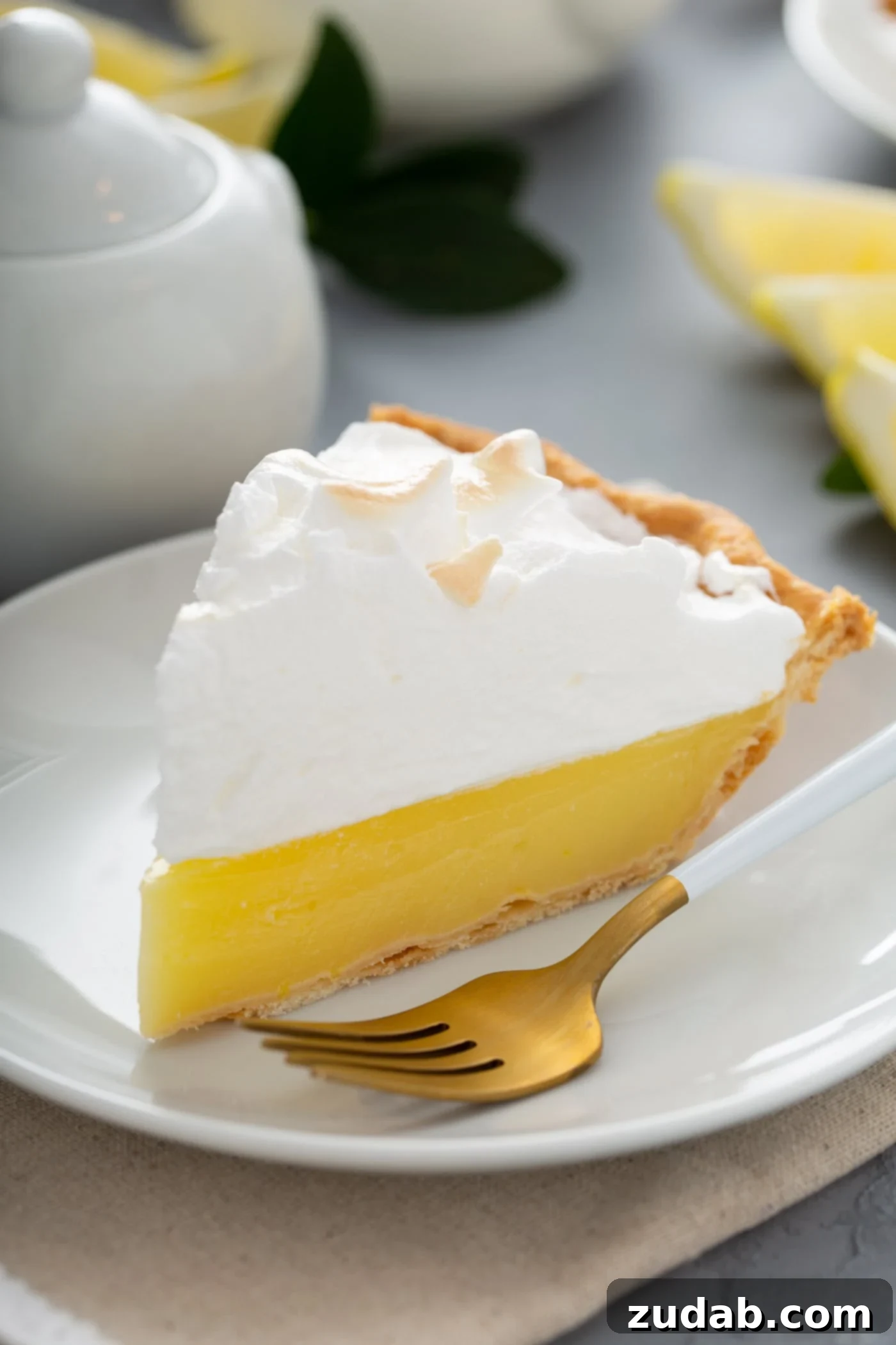 Freshly Baked Lemon Meringue Pie Slice A pristine slice of lemon meringue pie presented on a white dessert plate. A fork rests beside the pie, highlighting the vibrant yellow filling and lightly toasted meringue.