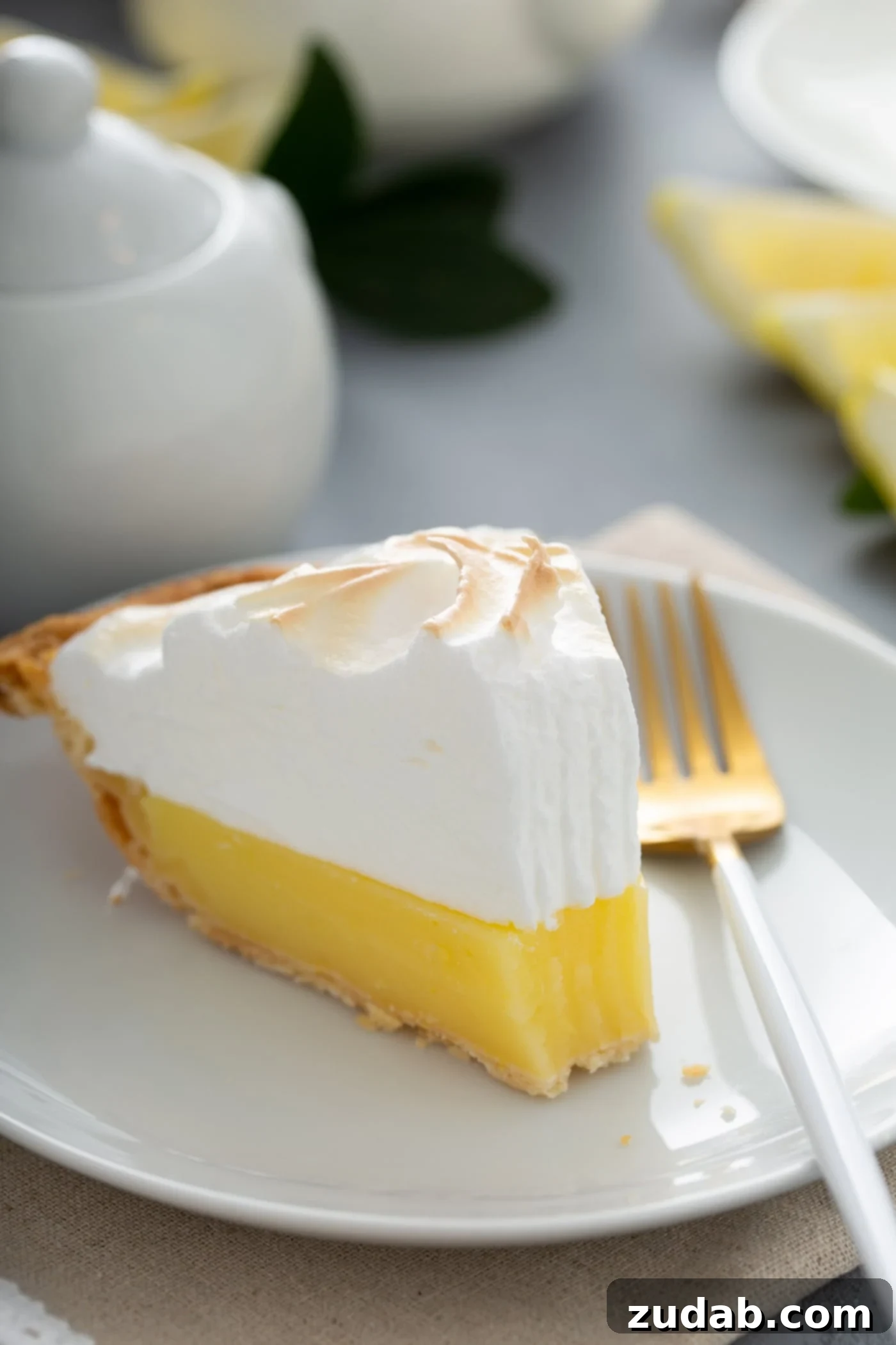 Enjoying a Slice of Lemon Meringue Pie A tantalizing slice of lemon meringue pie on a white dessert plate, with a fork resting nearby. A single bite has been taken, showcasing the vibrant filling and airy meringue.