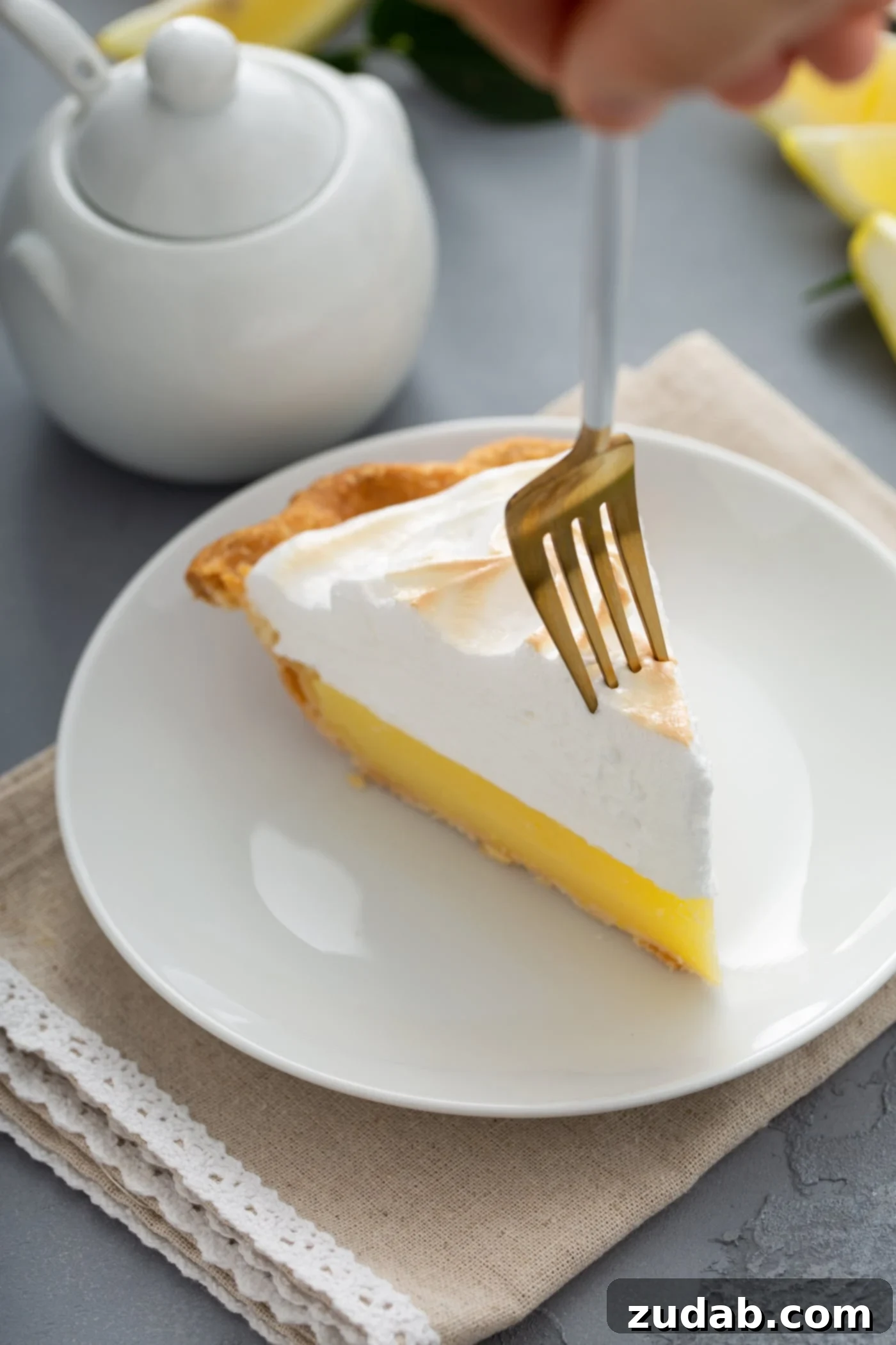 A Perfect Slice of Lemon Meringue Pie A delectable piece of lemon meringue pie is artfully presented, with a fork gently piercing the golden-brown peaks of the meringue, inviting a bite.