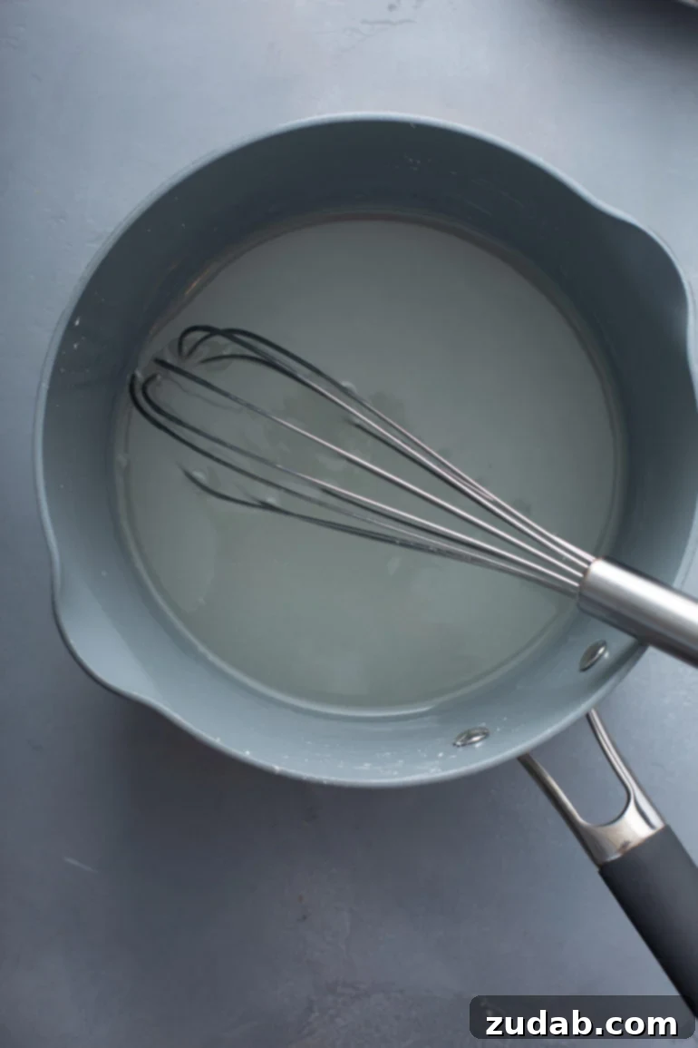 Mom's Secret Lemon Meringue Pie 4 A saucepan on the stove with a whisk, containing water, sugar, and cornstarch, illustrating the initial steps of making the lemon filling.