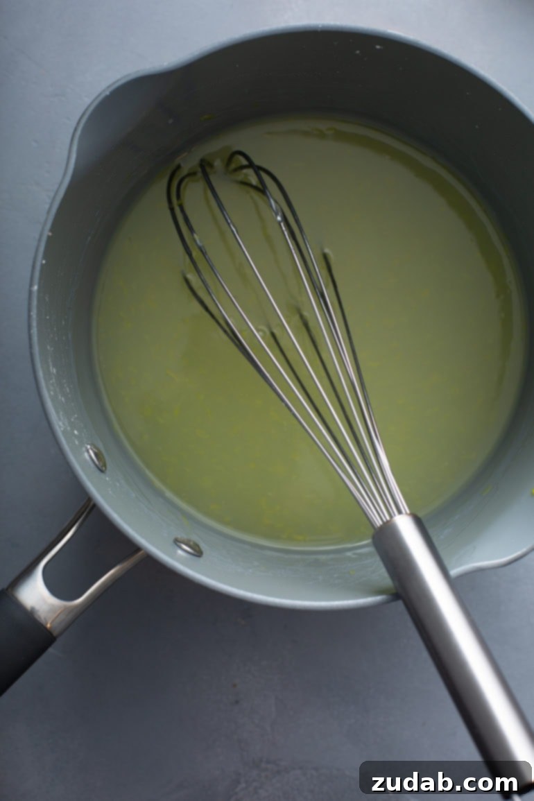 Mom's Secret Lemon Meringue Pie 5 A saucepan filled with glistening lemon pie filling, with a whisk resting in the creamy mixture, ready for the next stage of preparation.