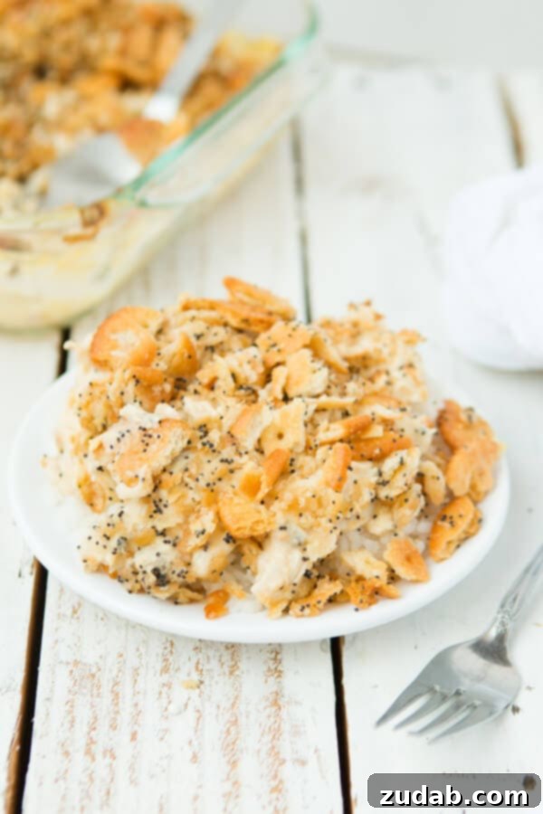 Everyone's favorite Poppy Seed Chicken Casserole with ritz crackers ohsweetbasil.com creamy chicken casserole with ritz crackers piled on top of white plate