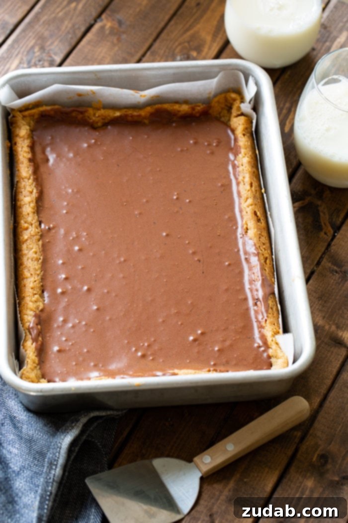 Irresistible Peanut Butter Bars 7 A 9x13 inch baking pan filled with freshly baked, uncut Peanut Butter Bars, generously topped with chocolate frosting.