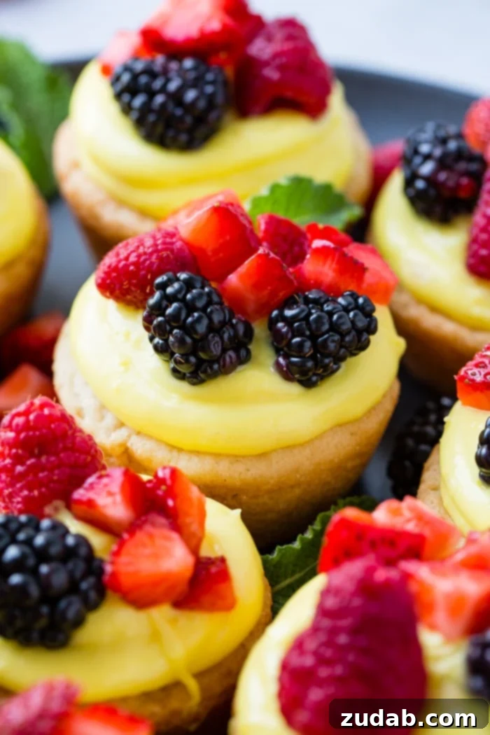 Zesty Lemon Fruit Cookie Cups 2 A dark pan with sugar cookie cups filled with lemon filling and topped with blackberries, raspberries and chopped strawberries