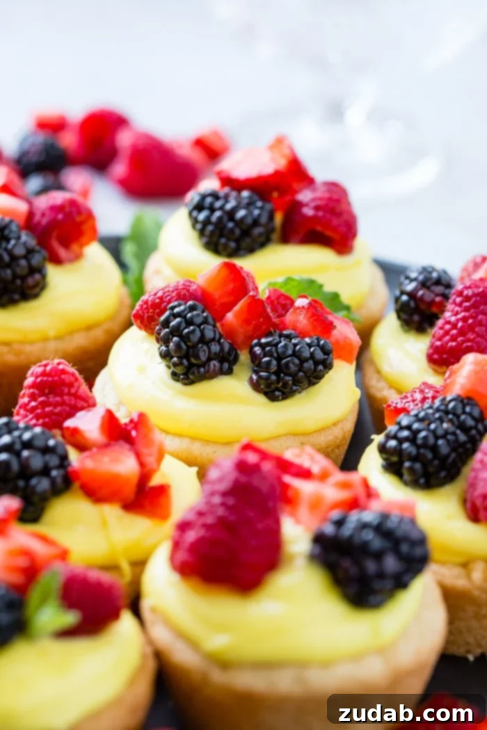 Zesty Lemon Fruit Cookie Cups 6 A dark pan with sugar cookie cups filled with lemon filling and topped with blackberries, raspberries and chopped strawberries