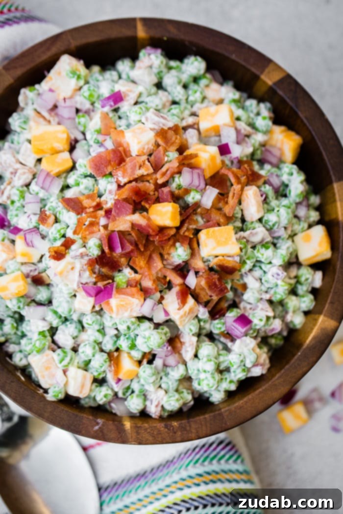 Creamy Southern Pea Salad 6 a wooden bowl full of creamy southern english pea salad with bacon, chunks of colby jack cheese