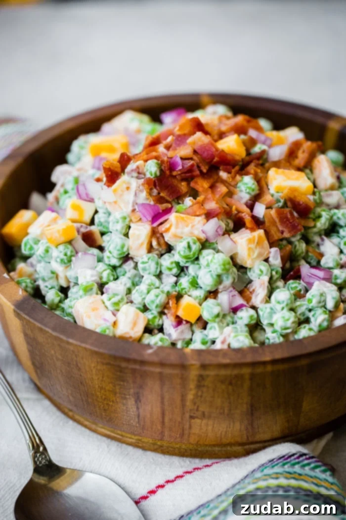 Creamy Southern Pea Salad 7 a wooden bowl full of creamy southern english pea salad with bacon, chunks of colby jack cheese