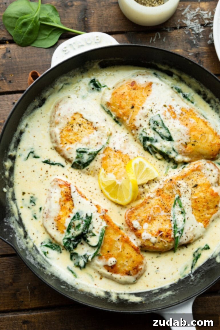 Chicken Florentine 3 Four golden pan-seared chicken breasts sitting in a creamy sauce with a slice of lemon and sautéed spinach