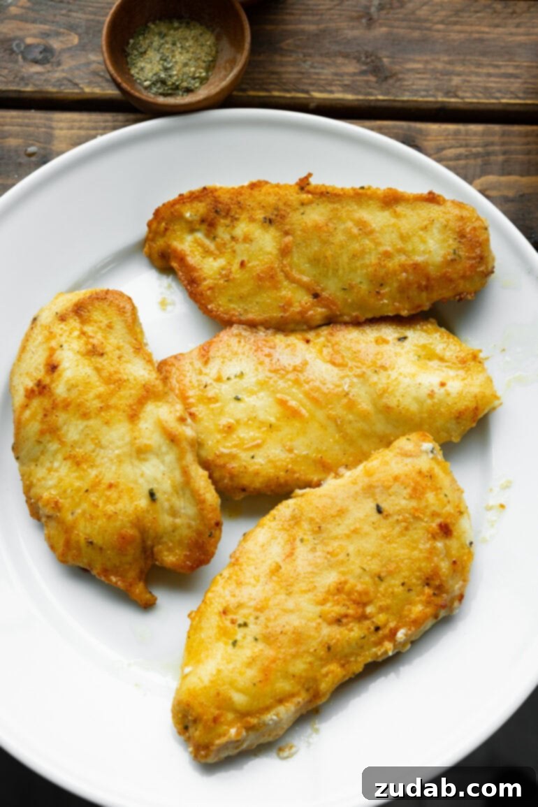 Chicken Florentine 5 Four lightly breaded, pan-seared golden chicken breasts resting on a white plate