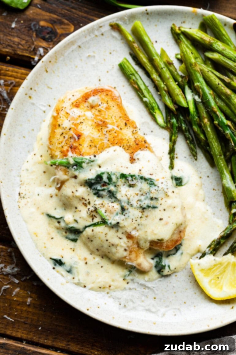 Chicken Florentine 10 A serving of Chicken Florentine on a white dinner plate with a side of cooked asparagus, ready to be enjoyed