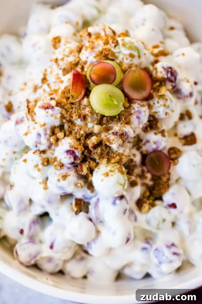 Creamy Southern Grape and Pecan Medley 3 A close-up view of a large white bowl filled with Southern Grape Salad, showcasing the plump red and green grapes, the creamy dressing, and a generous sprinkle of brown sugar pecans on top.