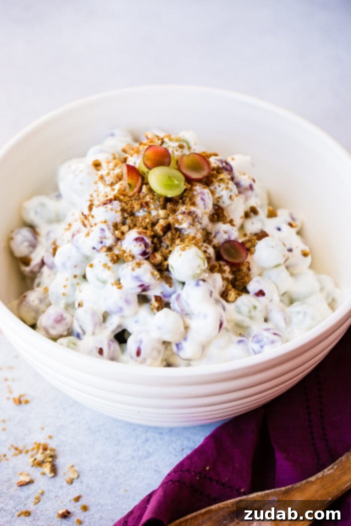 Creamy Southern Grape and Pecan Medley 5 A vibrant display of Southern Grape Salad with Pecans in a white bowl, highlighted by a scattering of fresh grapes and a generous topping of caramelized pecans.