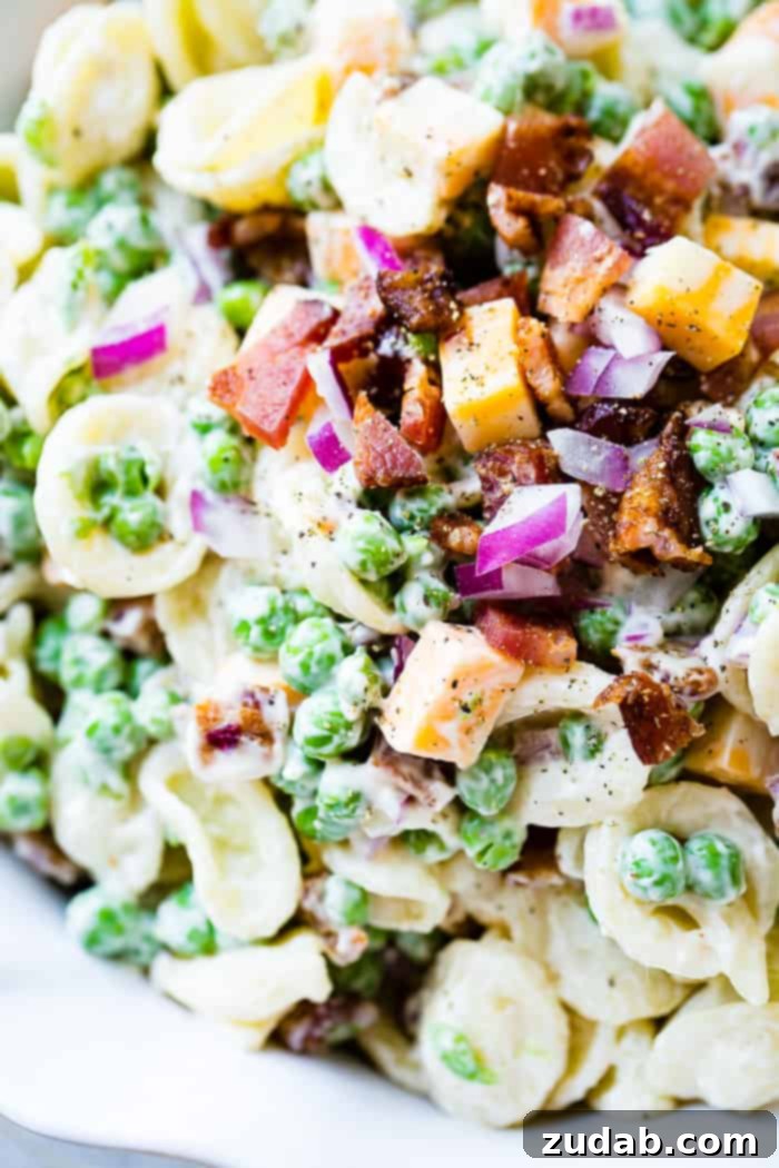 Southern Comfort Pea Pasta Salad 2 A white bowl with orchiette pasta, peas, cubed colby jack cheese, red onion and a simple dressing for the recipe southern pea pasta salad
