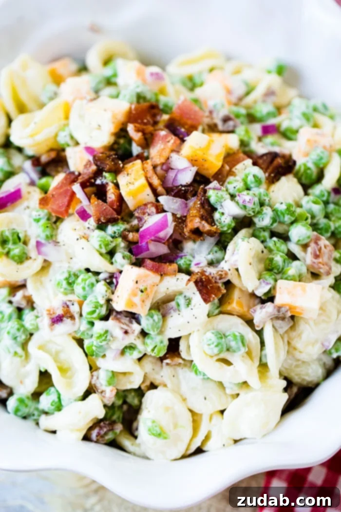 Southern Comfort Pea Pasta Salad 3 A white bowl with orchiette pasta, peas, cubed colby jack cheese, red onion and a simple dressing for the recipe southern pea pasta salad