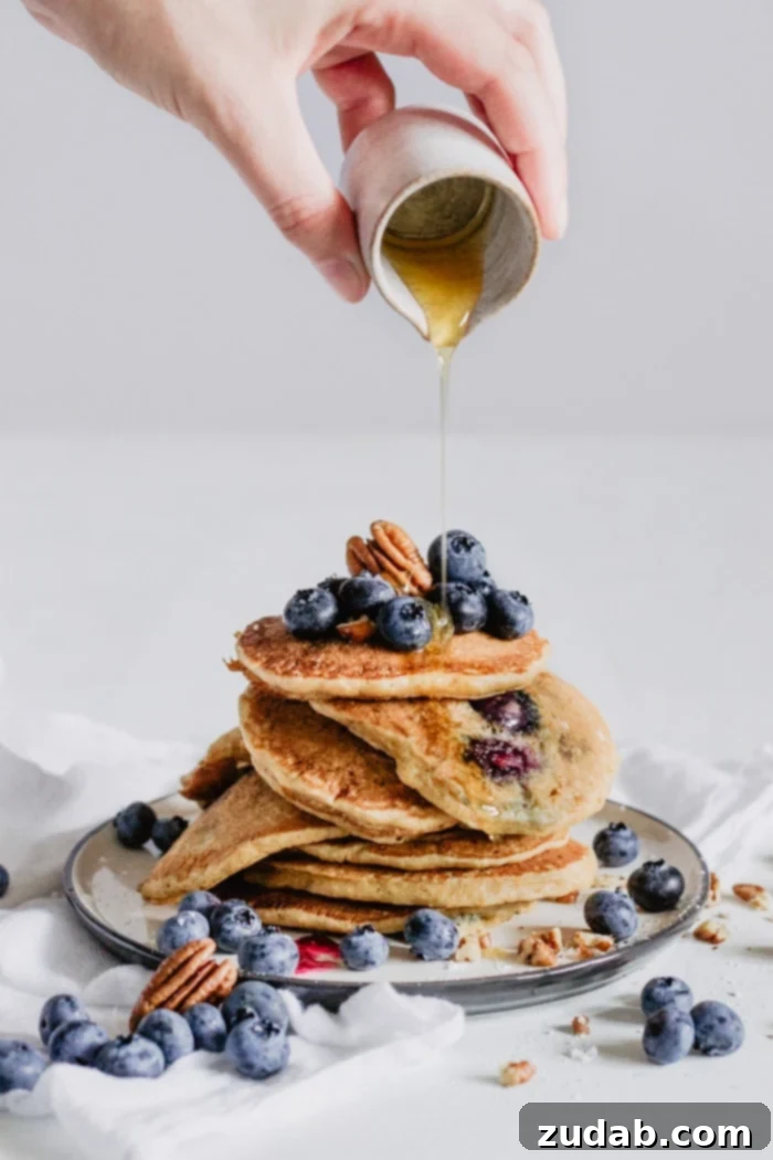 Ultimate Blueberry Pecan Pancakes 3 Close-up of a stack of homemade blueberry pecan pancakes with melted butter and syrup, showcasing their fluffy texture and delicious fillings.