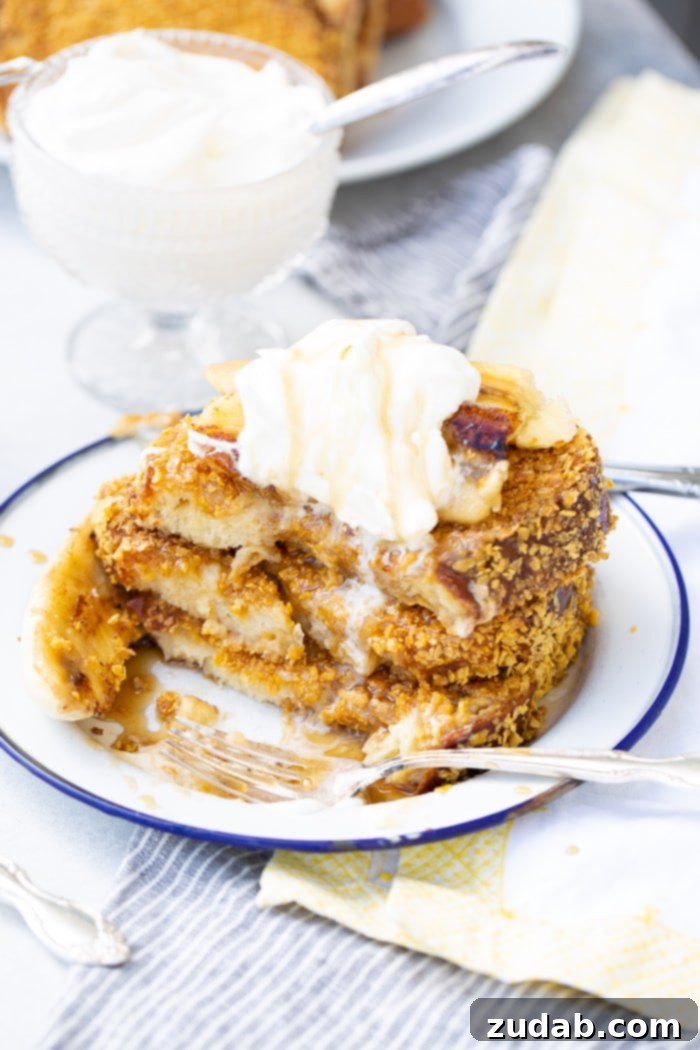 Cade's Signature Bananas Foster French Toast 6 A stack of golden brown, cornflake-crusted French toast, topped with rich bananas foster syrup and a dollop of whipped cream.