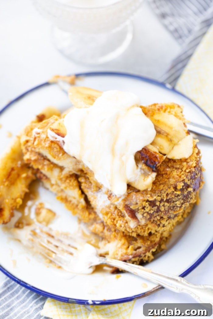Cade's Signature Bananas Foster French Toast 7 A stack of fluffy French toast, generously covered with bananas foster syrup and a dollop of whipped cream.