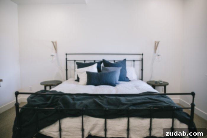 Stunning Basement Bedroom Makeovers 6 A tastefully decorated modern guest bedroom featuring a robust black iron bed frame with crisp grey bedding. The close-up showcases the inviting texture of the duvet and a selection of comfortable pillows, creating a welcoming and stylish sleeping space.