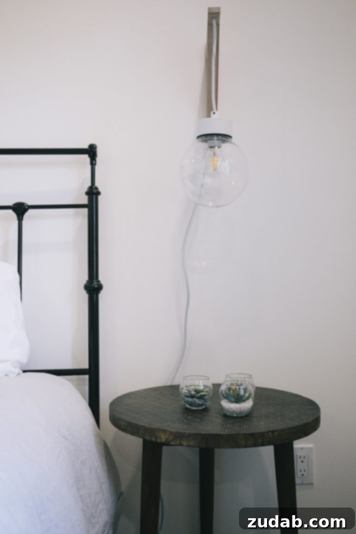 Stunning Basement Bedroom Makeovers 10 A modern glass globe pendant light hanging elegantly over a bedside table in a contemporary bedroom. The minimalist design of the light fixture adds a sophisticated touch, casting a soft glow that enhances the inviting ambiance of the space.