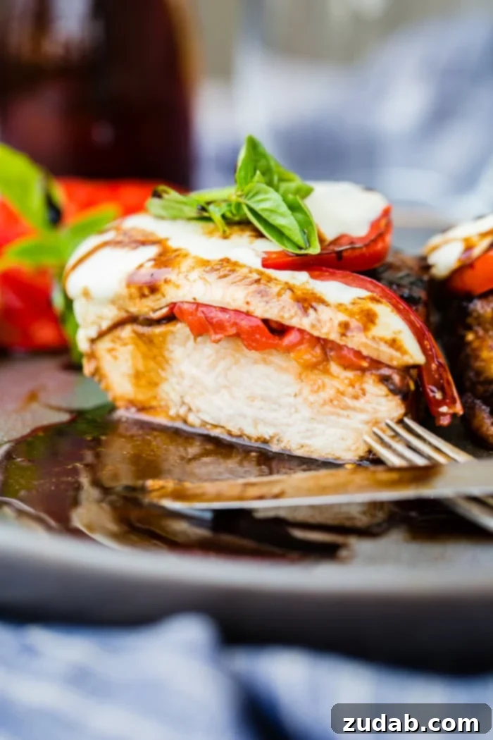 Balsamic Caprese Chicken plated, drizzled with glaze and garnished with fresh basil leaves
