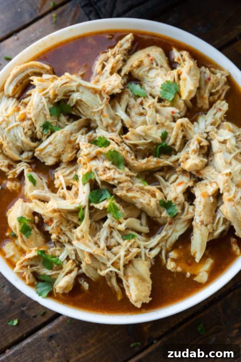 A close-up photo of juicy, seasoned shredded Cafe Rio chicken served in a shallow white serving bowl, ready to be enjoyed.