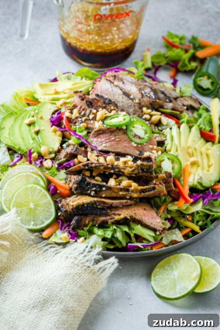Grilled Flank Steak with Zesty Thai Peanut Salad 4 A beautifully styled plate full of mixed greens, fresh vegetables, and tender flank steak marinated in a rich Thai peanut sauce, garnished with fresh lime, avocado slices, and jalapeño.