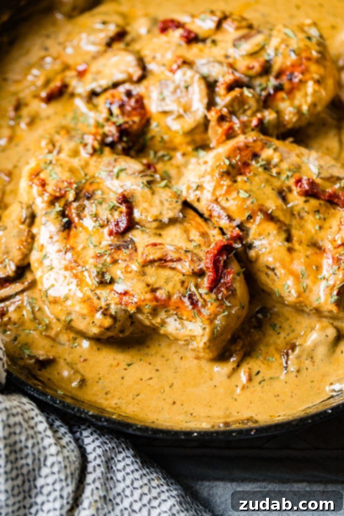 Effortless Creamy Herb Chicken with Sun-Dried Tomatoes 5 A black cast iron skillet with perfectly cooked chicken, a rich creamy sauce, sun-dried tomatoes, and fresh herbs.