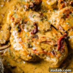 Effortless Creamy Herb Chicken with Sun-Dried Tomatoes 7 A black cast iron skillet with a creamy sauce full of sun dried tomatoes, mushrooms and seasoning over perfectly cooked chicken