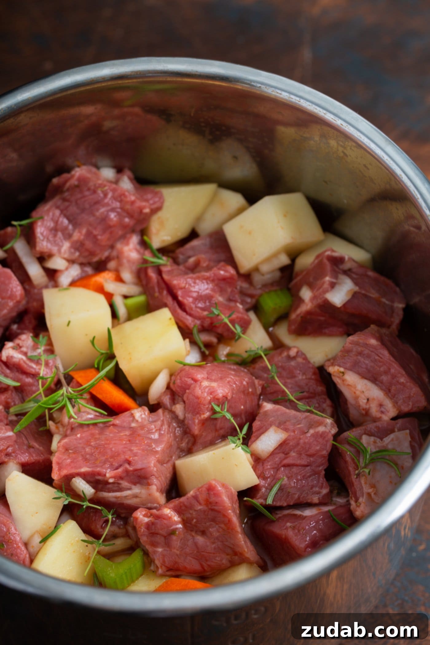 Instant Pot Beef Stew An instant pot with cubed beef, potatoes, carrots, and herbs.