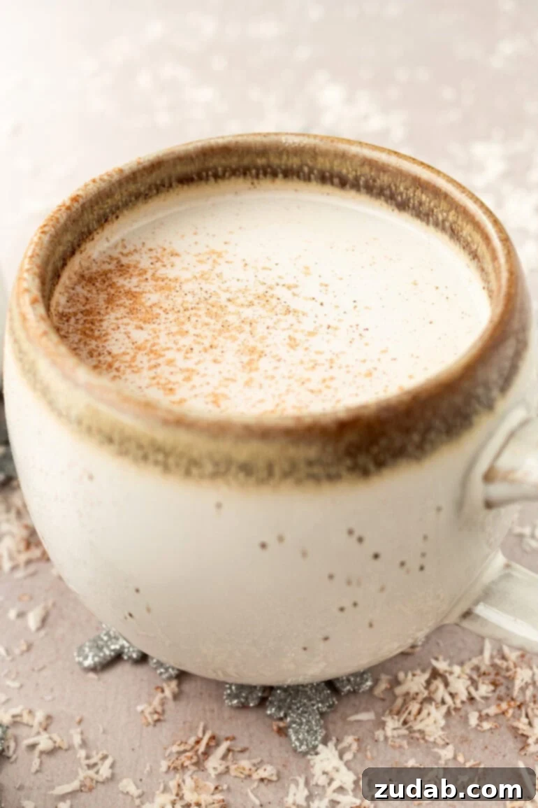 Snowman Milk Creamy White Hot Chocolate 2 A mug full of warm vanilla milk topped with a sprinkle of cinnamon, evoking cozy winter evenings.