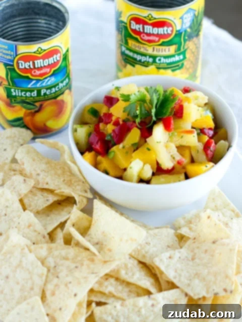 Embrace Everyday Joy 2 Freshly made peach pineapple salsa in a white bowl with tortilla chips on the side, ready to be enjoyed.