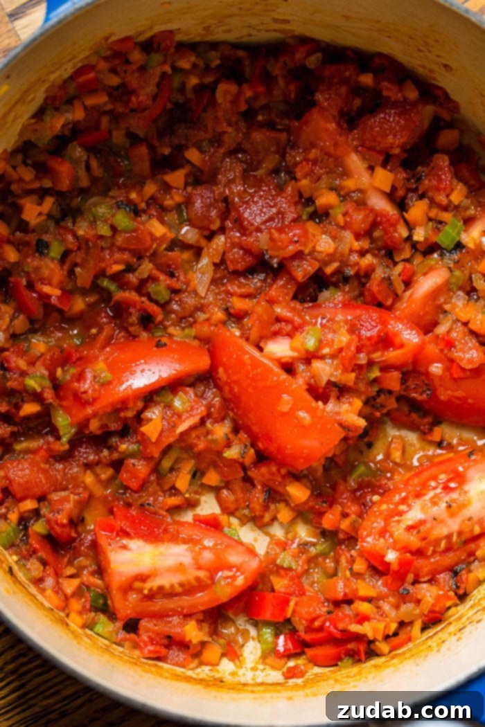 My Ultimate Chicken Tortilla Soup Recipe 3 A close-up photo of the vibrant and rich base for chicken tortilla soup, featuring sautéed onions, carrots, bell peppers, celery, and ripe Roma tomatoes, along with canned fire-roasted tomatoes.