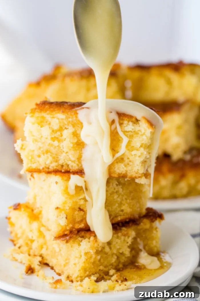 The Ultimate Moist and Sweet Cornbread Recipe with Video 3 A delectable photo showcasing three pieces of homemade sweet cornbread stacked high, with a luscious stream of honey butter gracefully drizzling over them.