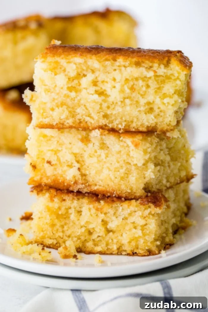 The Ultimate Moist and Sweet Cornbread Recipe with Video 4 A stunning photo of three perfectly golden-brown pieces of sweet, moist cornbread, stacked neatly on top of each other, ready to be enjoyed.