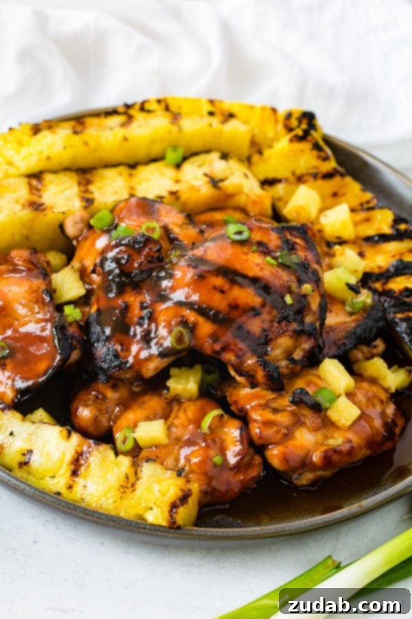 Easy Huli Huli Grilled Chicken Video Guide 4 A photo of grilled huli huli chicken with grilled pineapple in the background.