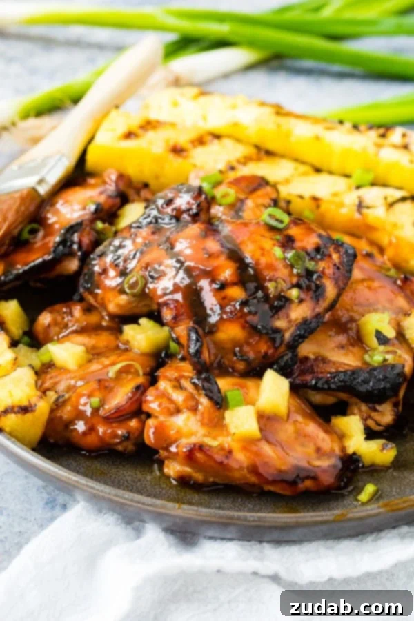 Easy Huli Huli Grilled Chicken Video Guide 5 A photo of grilled huli huli chicken with grilled pineapple in the background.
