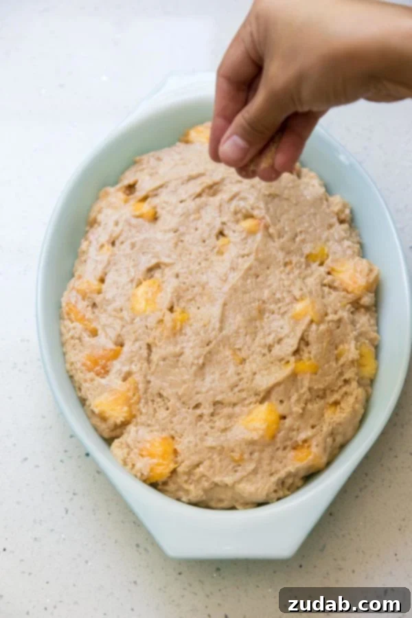 Golden Peach Butter Cake 4 Peach dump cake batter being poured into a greased baking pan