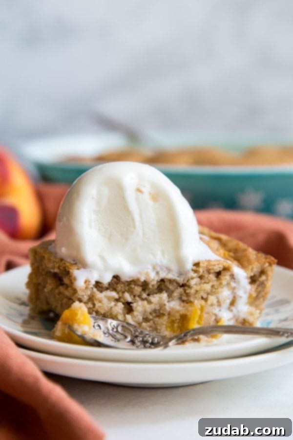 Golden Peach Butter Cake 6 A slice of peach dump cake on a plate, topped with a scoop of vanilla ice cream