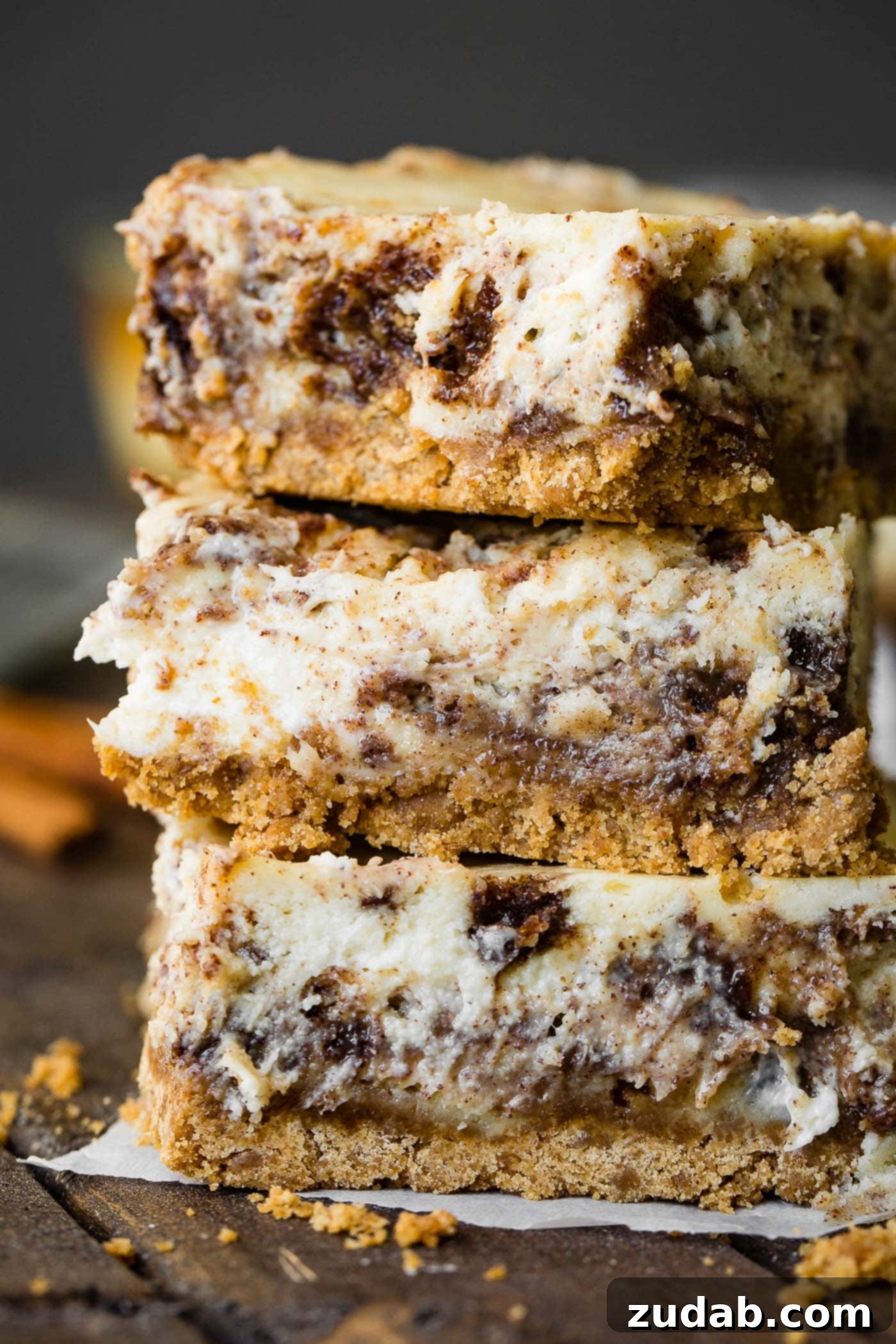 Easy Blender Cinnamon Roll Cheesecake Bars 2 A photo of three cinnamon roll cheesecake bars stacked on top of each other, ready to be served.
