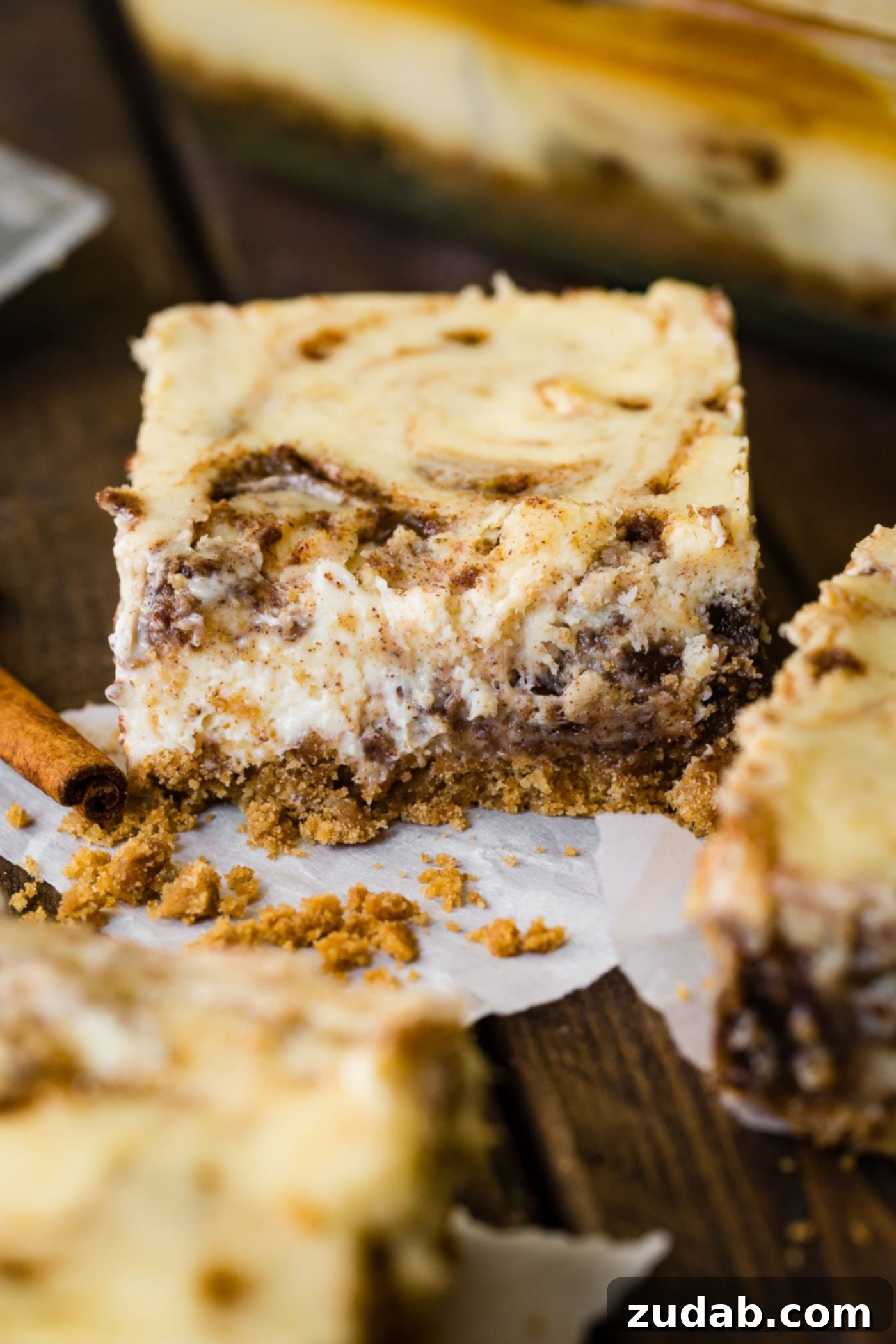 Blender Cinnamon Rolls Cheesecake Bars A close-up photo of a single cinnamon roll cheesecake bar, emphasizing the texture and cinnamon swirl.