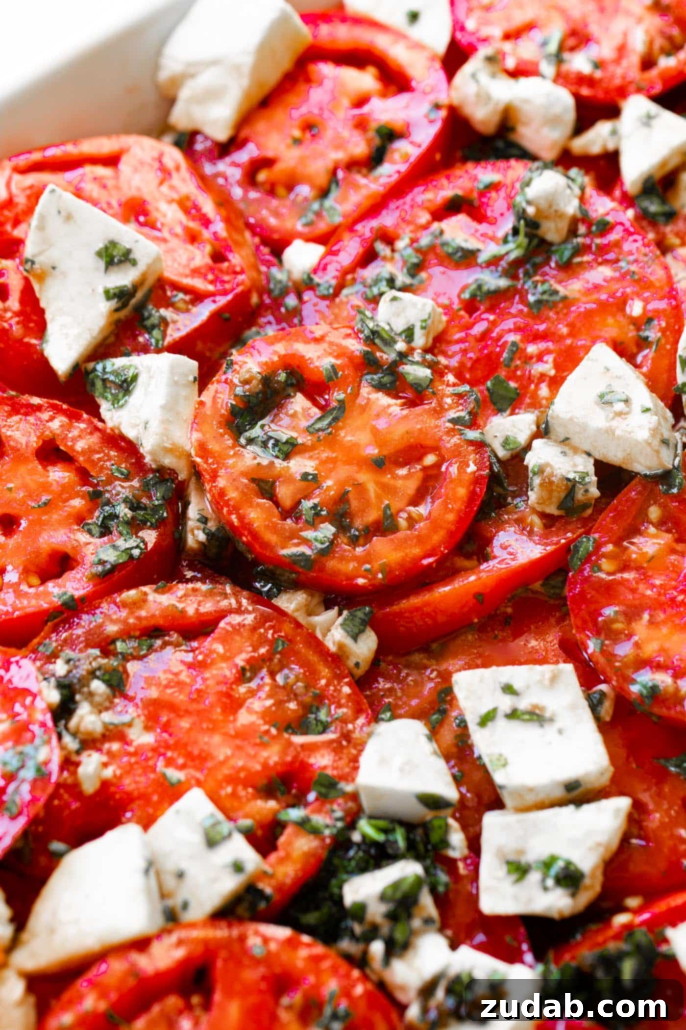 3 Cheese Marinated Tomatoes Salad A close-up shot of the stunning 3-Cheese Marinated Tomato Salad, highlighting the colorful tomatoes, fresh green herbs, and delicious cheese crumbles.