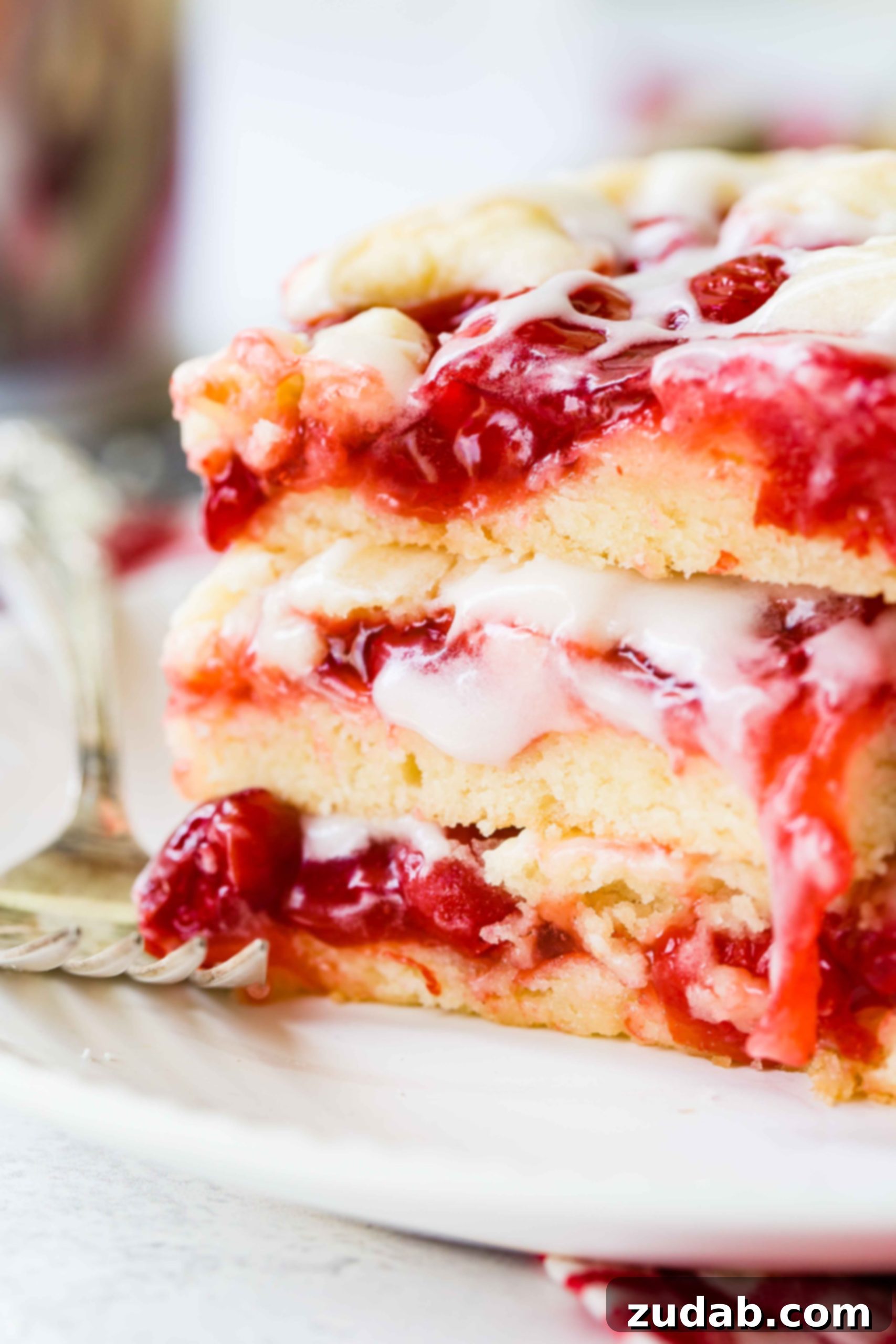 Sweet Cherry Sugar Cookie Bars 2 A stack of three glistening cherry pie bars, drizzled with a sweet glaze and ready to be enjoyed.