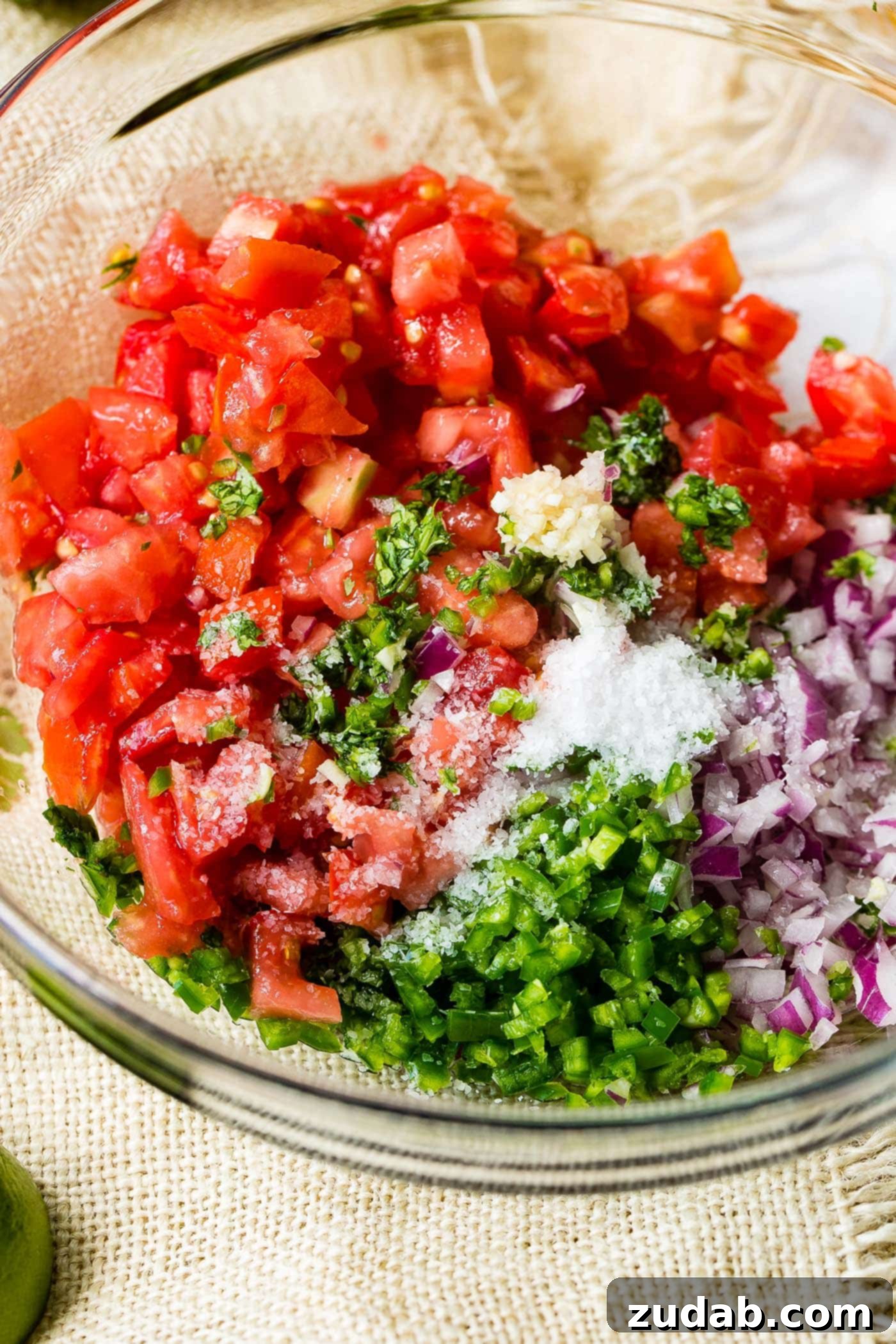 Fresh Pico de Gallo Ingredients A glass bowl filled with the freshly chopped ingredients for Pico de Gallo, before being stirred together, highlighting their individual textures and colors.