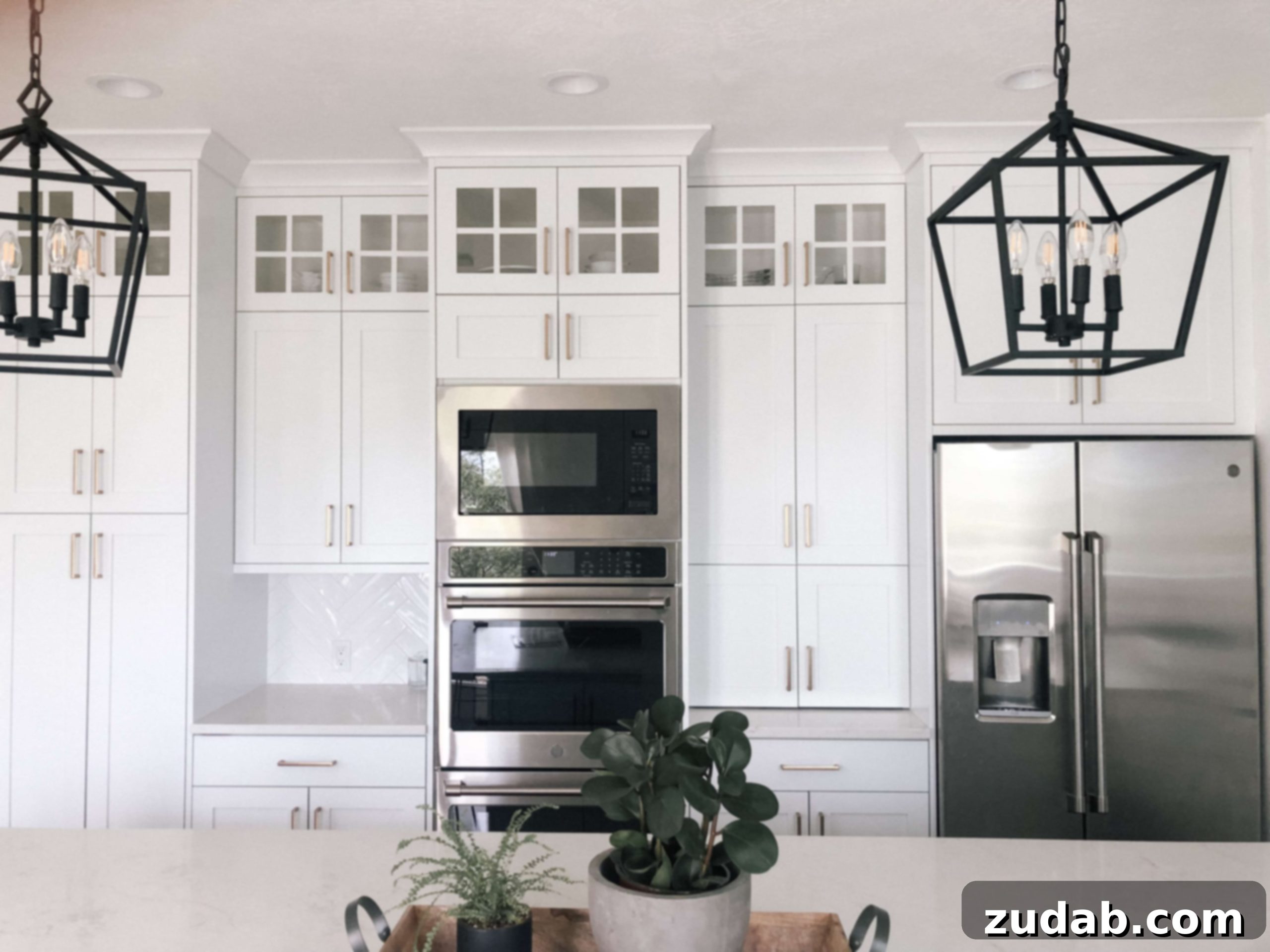 Overview of a spacious all-white kitchen, highlighting the extensive island, pristine white cabinets, and carefully chosen black and wood accents