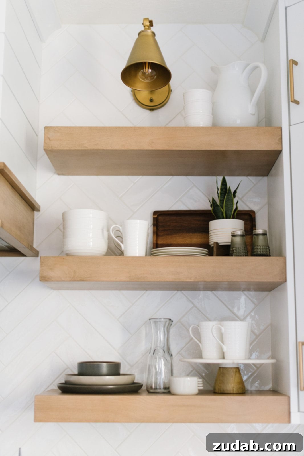 Modern all-white kitchen featuring a spacious island, elegant countertops, clear glass upper cabinets, and stylish black lantern pendant lighting